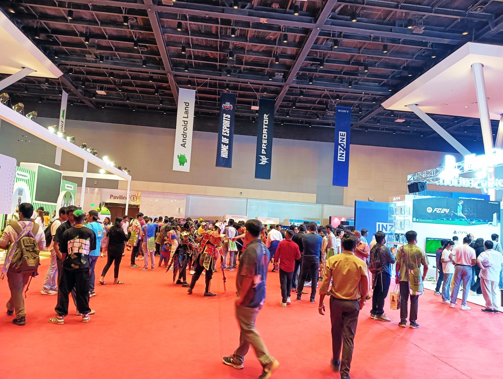 Exhibition Hall Venue Branding — Hanging pavilion branding, aisle signage and hall graphics across a full exhibition floor.