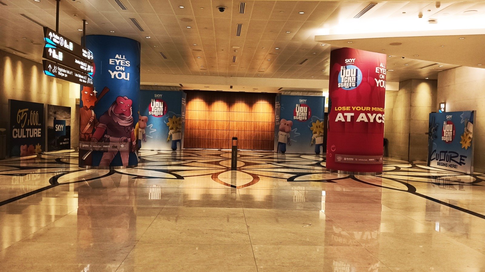 Lobby Pillar Branding — Full-height pillar graphics and standees dressing a convention centre lobby.